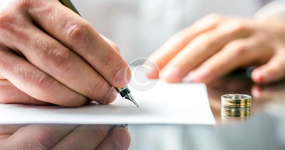 Un abogado de familia firmando un documento con un anillo de bodas.
