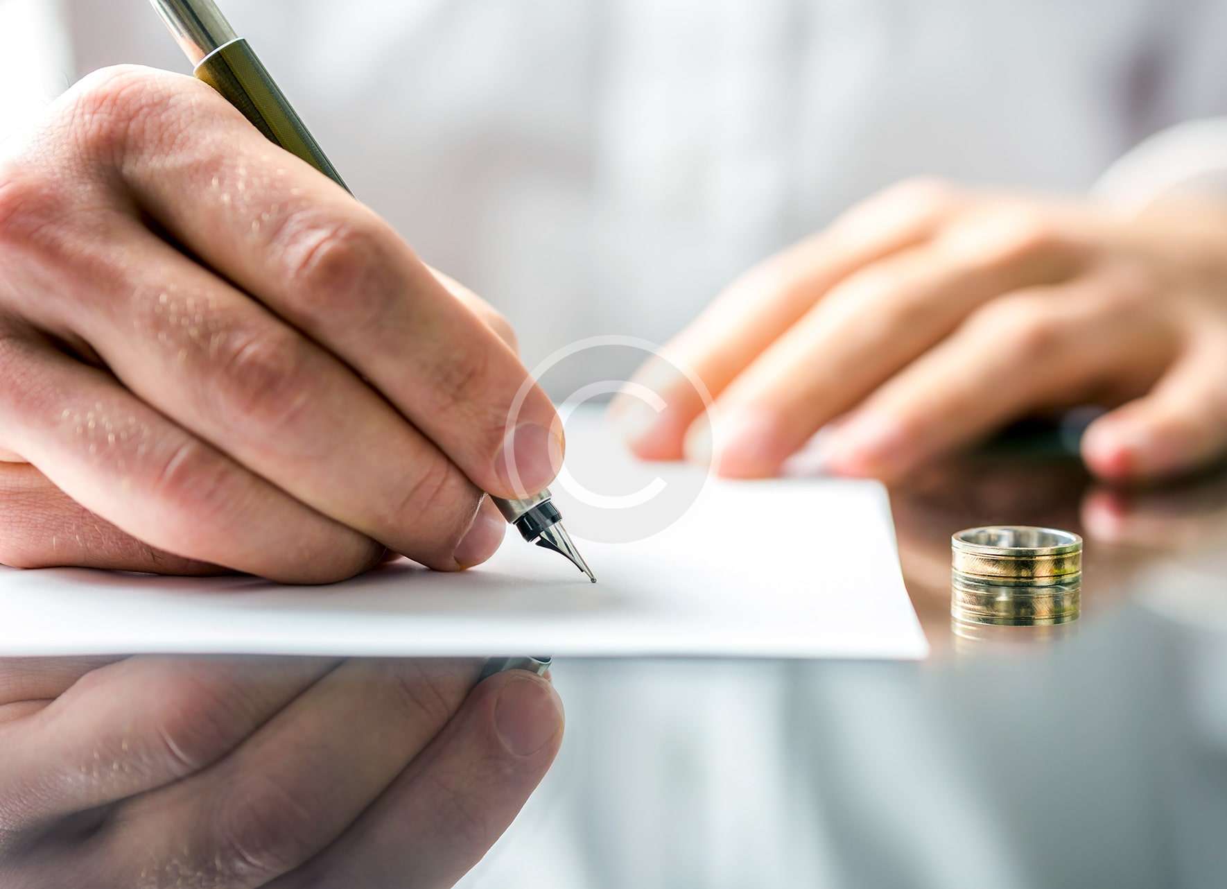 Un abogado de familia firmando un documento con un anillo de bodas.
