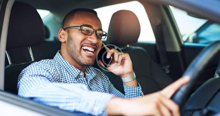 Un hombre habla por teléfono celular mientras conduce un automóvil y busca asesoramiento legal sobre asuntos familiares de un abogado de familia.