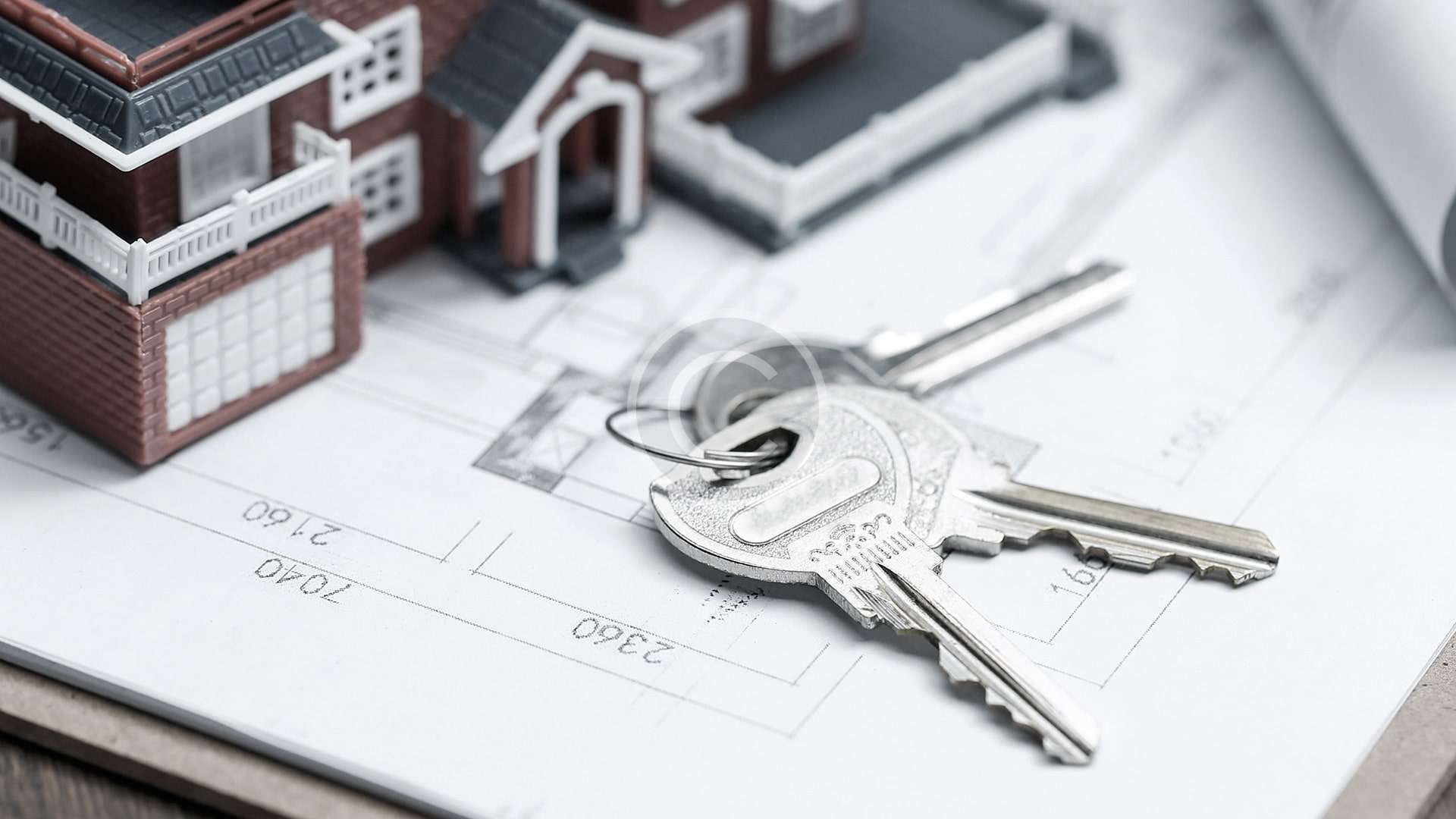 Llaves de una casa modelo encima de un plano, elaborado por un abogado de familia.